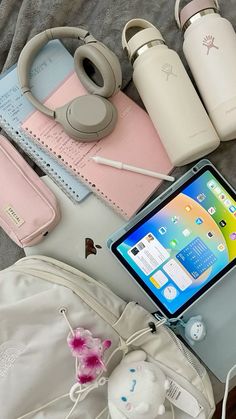 an assortment of personal items laid out on a bed next to a laptop and headphones