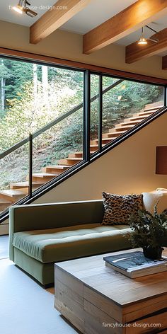 a living room filled with furniture and a large window next to a stair case that leads up to the second floor