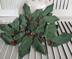 a white plate topped with green leaves and red berries