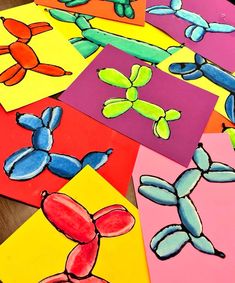 colorful paper cut outs with different shapes and sizes on the table in front of them