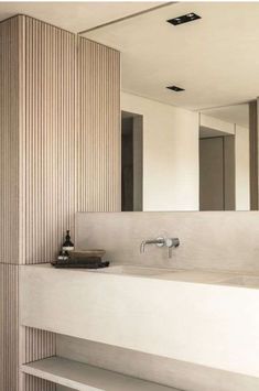 a bathroom sink sitting under a mirror next to a wooden wall mounted faucet