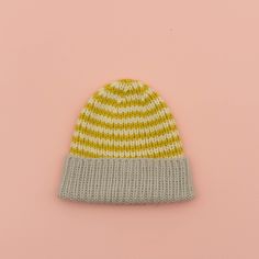 a yellow and white knitted hat on a pink background