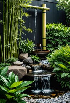 a small waterfall in the middle of a garden with bamboo trees and plants around it