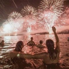 people are in the water watching fireworks go off over them and on their stomachs