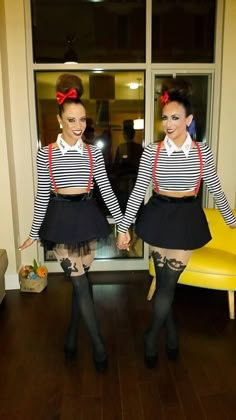 two young women dressed in black and white striped shirts holding hands while standing next to each other