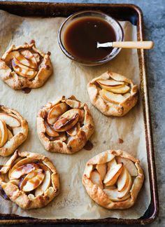 apple pies on a baking sheet with caramel sauce in the middle and apples sliced up