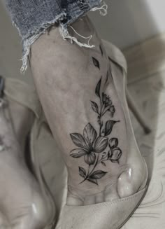 a woman's foot with a flower tattoo on the left side of her leg