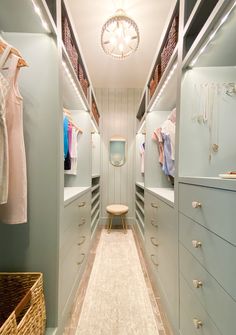 a walk in closet with lots of drawers and clothes hanging on the wall above it