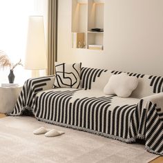 a black and white couch sitting on top of a rug next to a lamp in a living room