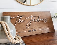 a wooden sign sitting on top of a table next to a vase filled with flowers