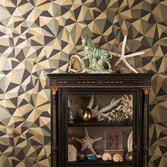 a shelf with shells and other items on it in front of a geometric wallpaper