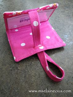 a pink wallet with white polka dots on it sitting on top of a cement floor