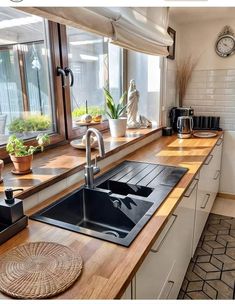 a kitchen sink sitting under a window next to a counter top with a clock on it