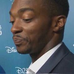 a close up of a person wearing a suit and tie in front of a blue background