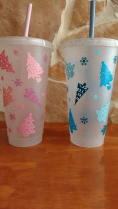 two plastic cups with straws in them sitting on a table