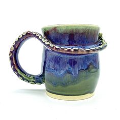 a blue and green mug with an octopus handle on it's side, sitting in front of a white background