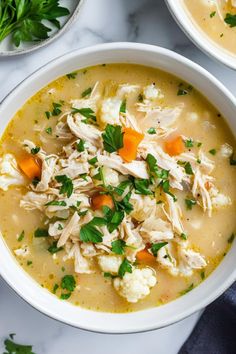 two bowls filled with chicken and cauliflower soup