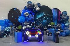 a video game controller surrounded by balloons and streamers in front of a party backdrop