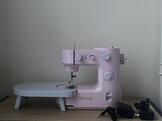 a pink sewing machine sitting on top of a wooden table