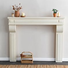 a white fireplace mantel with plants and candles on top