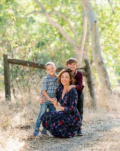 a woman and two boys posing for a photo in the woods