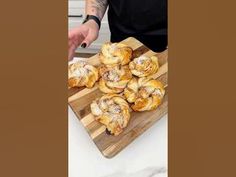 a man standing in front of a cutting board filled with pastries