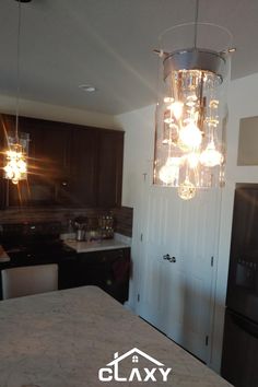 a kitchen area with a refrigerator, sink and lights hanging from the ceiling above it