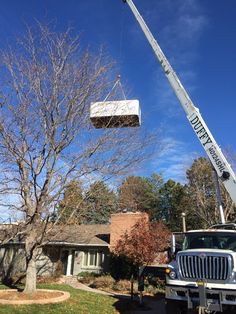 a man on a cherry picker working on a tree in front of a house