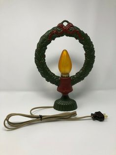 a christmas light with a cord attached to it and a green ornament on top