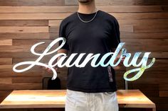 a man standing in front of a wooden wall with the word laundry written on it