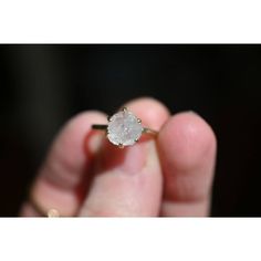 a person holding an engagement ring with a diamond in it's middle finger, close up