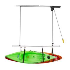 a green and red kayak is suspended by two black hooks on a white background