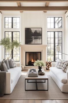 a living room filled with furniture and a fire place in front of two large windows