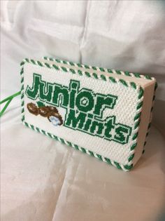 a cross stitch name tag with the word junior whiss written in green and white