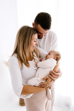 a man and woman holding a baby in their arms