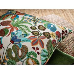 two decorative pillows sitting on top of a rug next to each other, one has a green pillow and the other has a colorful floral design