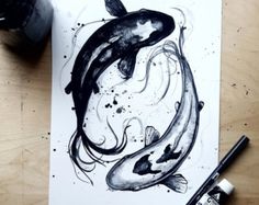 a black and white drawing of two koi fish on paper with watercolor pencils next to it