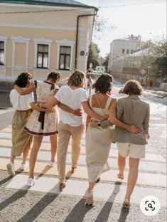 four women walking across a crosswalk in front of a yellow building on a sunny day