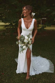 a woman in a white dress holding a bouquet and posing for the camera with her legs crossed