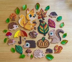 a bunch of small cross stitched animals and leaves on a wooden table with some green leaves around them