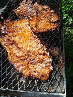 two steaks are cooking on the grill outside