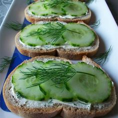 four slices of bread with cucumber and dill on them sitting on a plate