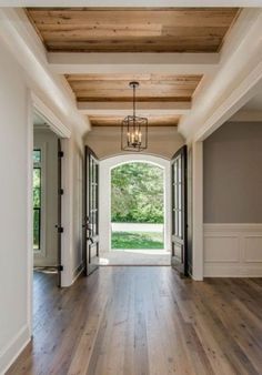 an open door leading into a large room with wood flooring and white trim on the walls