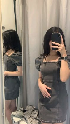 a woman taking a selfie in front of a mirror while wearing a denim dress