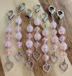 several pink beads and charms on a wooden surface