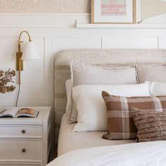 a bed with white sheets and pillows next to a lamp on a nightstand in a bedroom