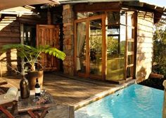 a small wooden house with a pool in the middle and patio furniture on the outside