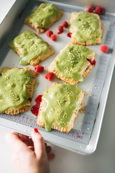 there are many small pastries with green toppings on the baking sheet, ready to go into the oven