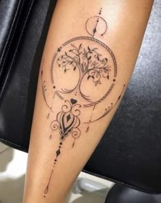 a woman's leg with a tree and swirls tattoo on her left calf