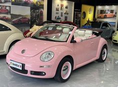 a pink convertible car is parked in a showroom